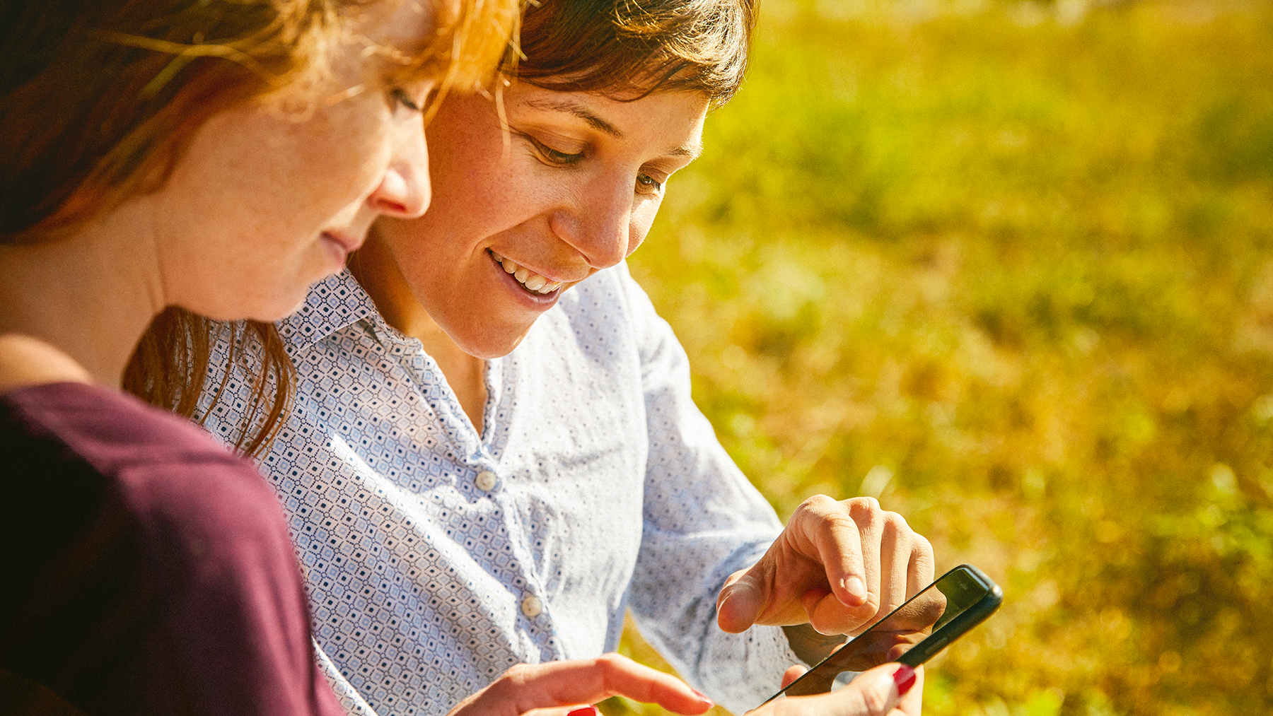 Deux femmes utilisant une application mobile de tourisme en plein air, symbole de la digitalisation des services touristiques.
